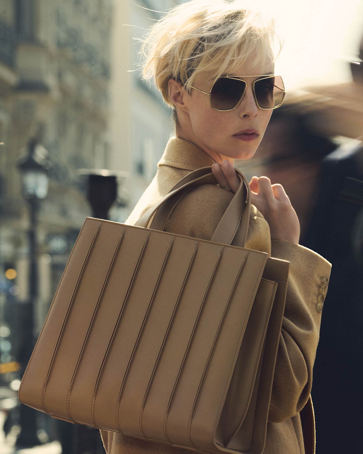 Model with large Max Mara Whitney Bag 7 detail, in camel-coloured leather with prominent vertical stitching.